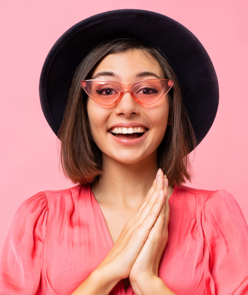 Happy cute girl in pink dress posing in studio.